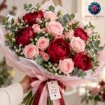 Bouquet di peonie rosse e rose rosa chiaro con eucalipto, disponibile da Rosa Fiorista Milano.