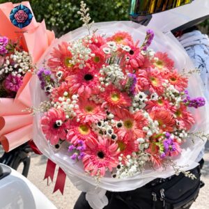 Bouquet di Gerbere Rosa with pink gerberas, white gypsophila, purple accents and white wrapping in Milano.
