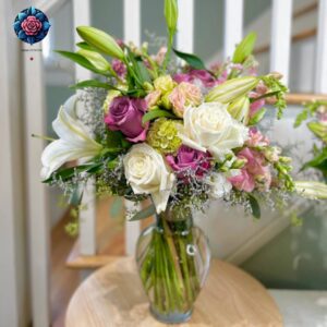 Mix Bouquet 031 with white lilies, ivory and mauve roses, pink flowers and greenery in a glass vase